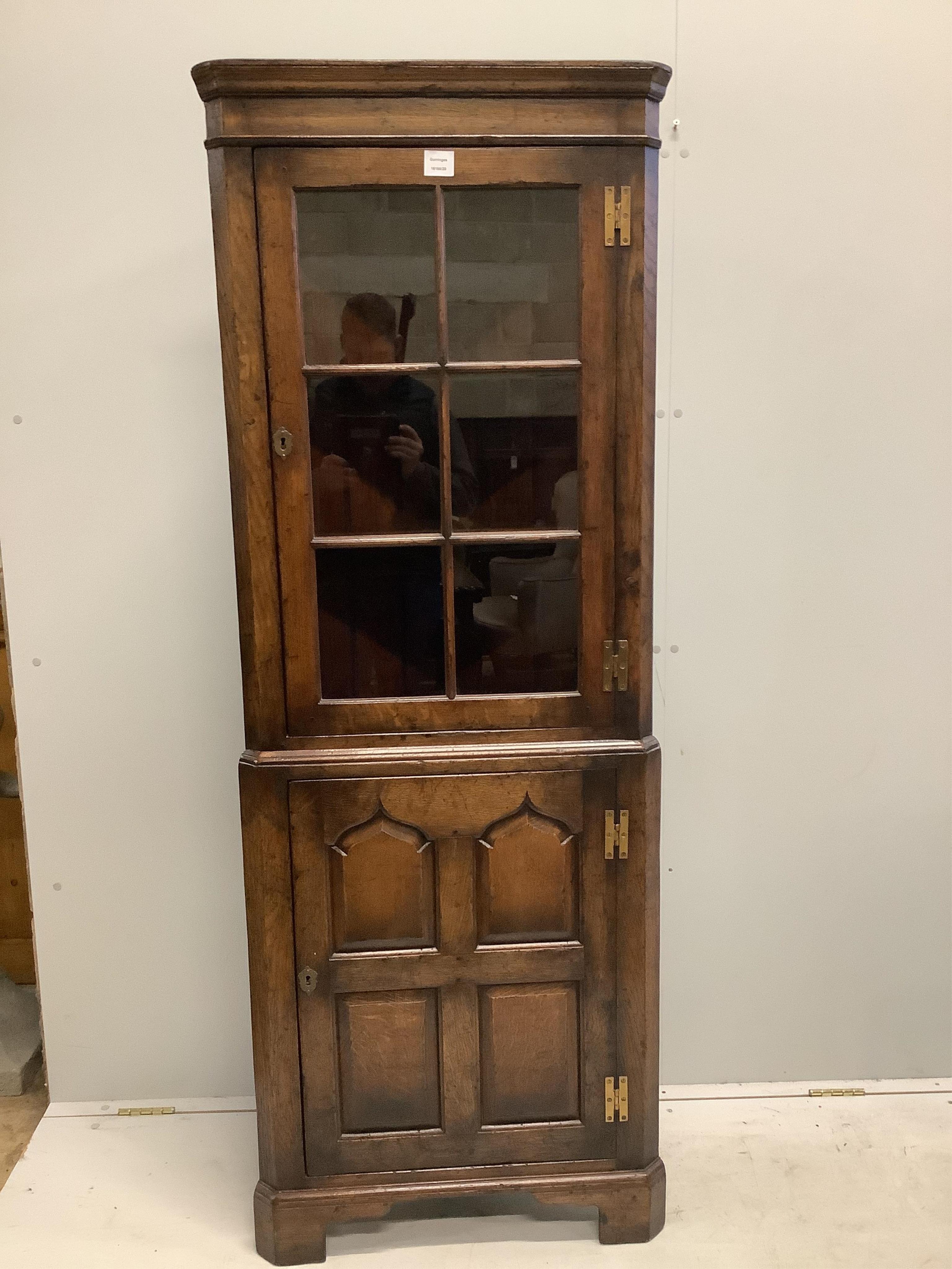 An 18th century style oak two part standing corner cupboard, the glazed barred top, over a fielded panelled door, width 64cm, depth 34cm, height 176cm. Condition - good